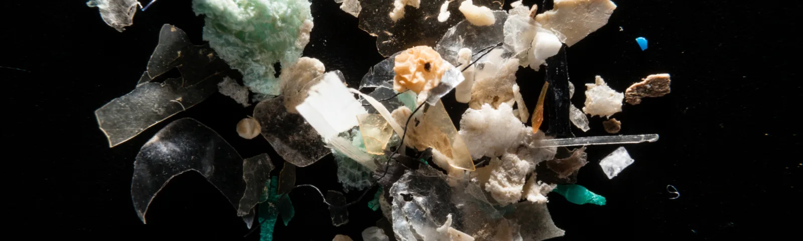 Nærbilde av ulike former og farger av mikroplast på sort bakgrunn