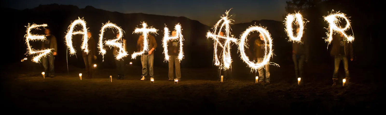 Lysende bokstaver som staver Earth Hour i mørket