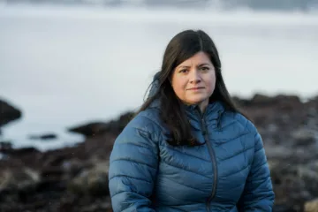 Karoline Andaur ved i strandsonen med havet i bakgrunnen. Hun har på seg blå vinterjakke.