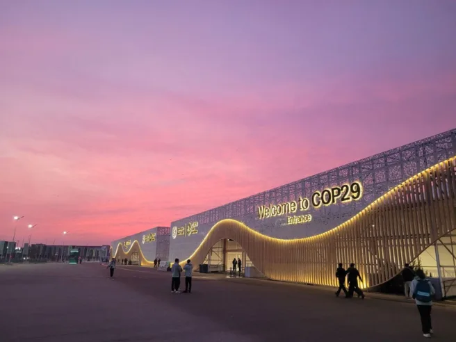 Bilde av en bygning der det står "Welcome to COP 29". Rosa himmel over.
