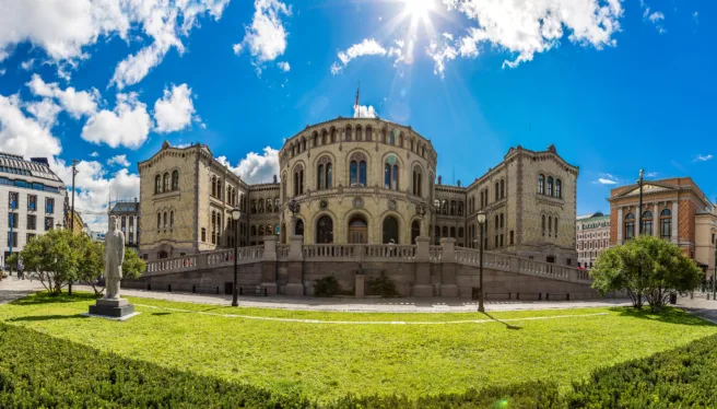 Stortingen på en sommerdag med grønn plen foran